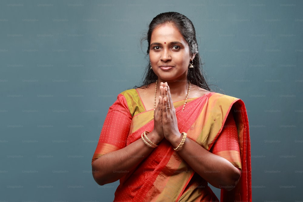 La donna dell'India meridionale vestita tradizionalmente saluta con le mani giunte