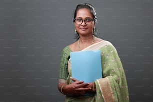 Portrait of a smiling woman wearing sari and holding a file in hand