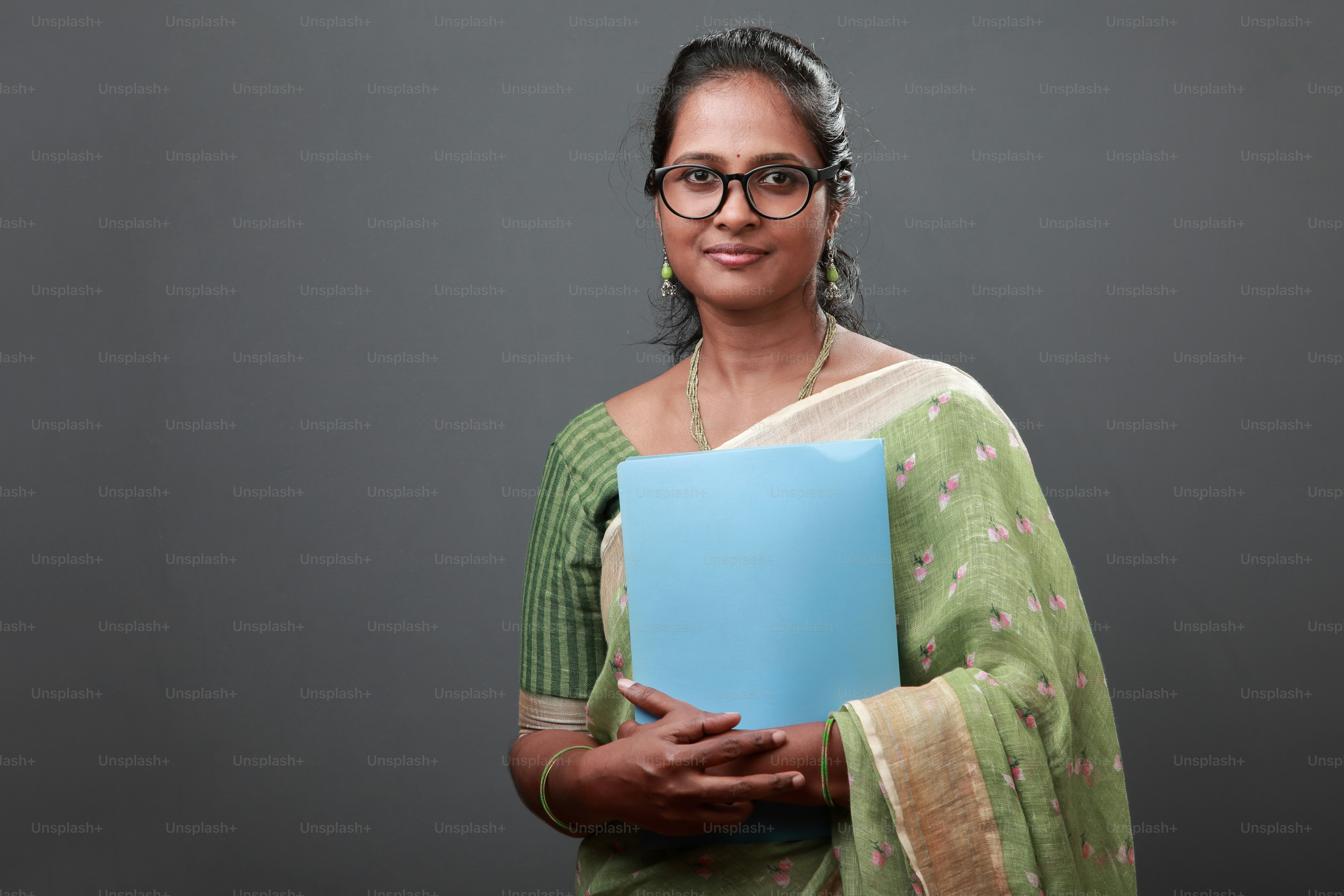 Portrait of a smiling woman wearing sari and holding a file in hand