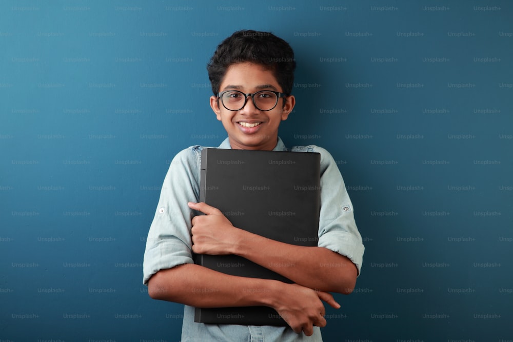 Retrato de um menino jovem feliz segurando um laptop na mão