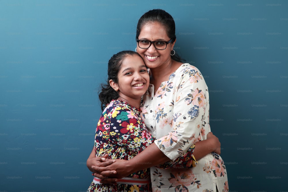 Mãe e filha sorridentes de etnia indiana abraçando-se juntos