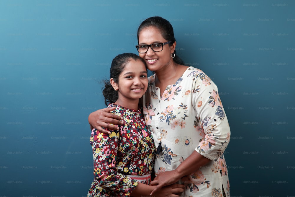 Mãe e filha sorridentes de etnia indiana abraçando-se juntos