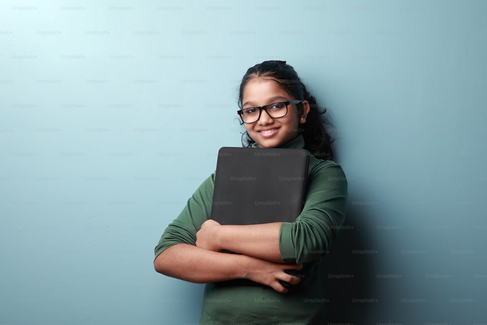 Menina feliz de origem indiana segura um computador portátil