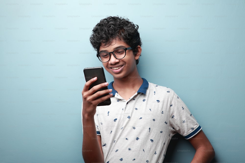 Joven sonriente de origen indio mirando su teléfono móvil