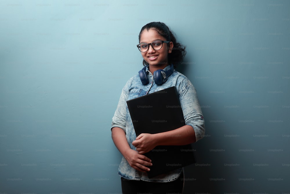 Glückliches Mädchen indischer Herkunft hält einen Laptop in der Hand