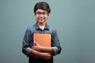 Smiling boy of Indian ethnicity holding note books in his hands