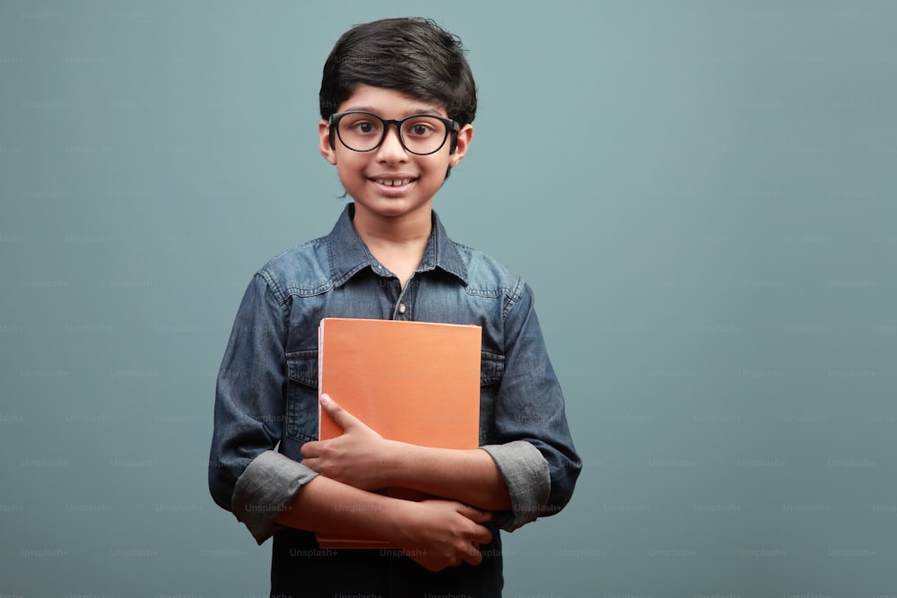 Garçon souriant d’origine indienne tenant des carnets de notes dans ses mains