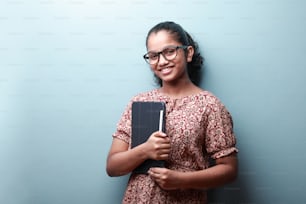 Retrato de uma menina sorridente da etnia indiana segurando um telefone tablet na mão