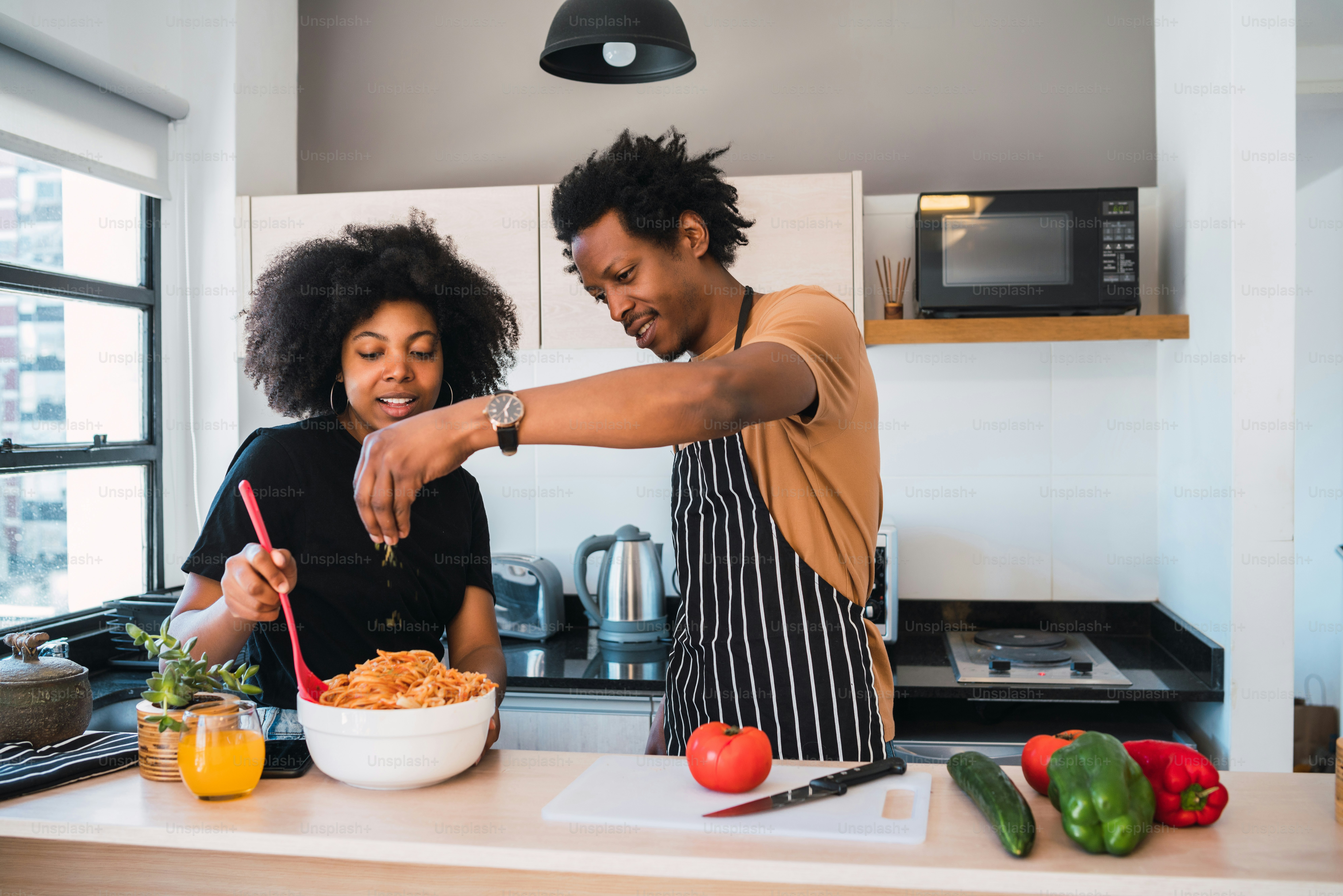 Portrait of young afro couple cooking together in the kitchen at home. Relationship, cook and lifestyle concept.