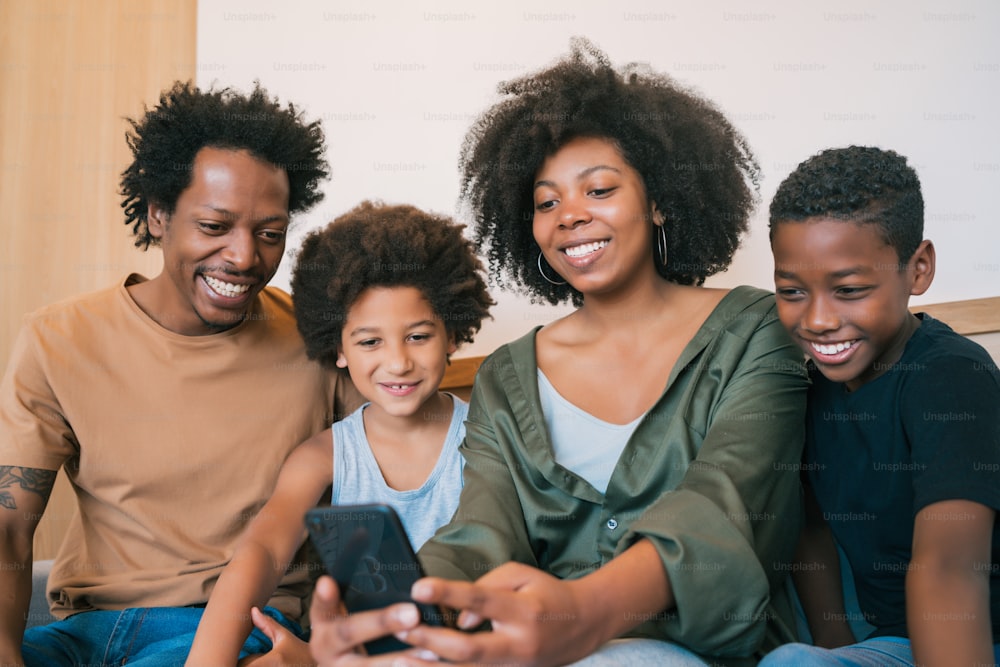 Retrato de una familia afroamericana tomándose una selfie junto con el teléfono móvil en casa. Concepto de familia y estilo de vida.