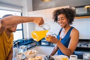 Retrato do jovem casal feliz tomando café da manhã juntos em casa. Conceito de relacionamento e estilo de vida.