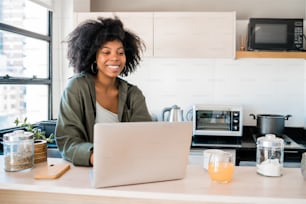 Portrait of young latin woman using laptop at home. Home office and technology concept.
