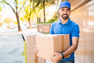 Portrait of a delivery man courier with cardboard boxes in hands outdoors. Delivery and shipping concept.