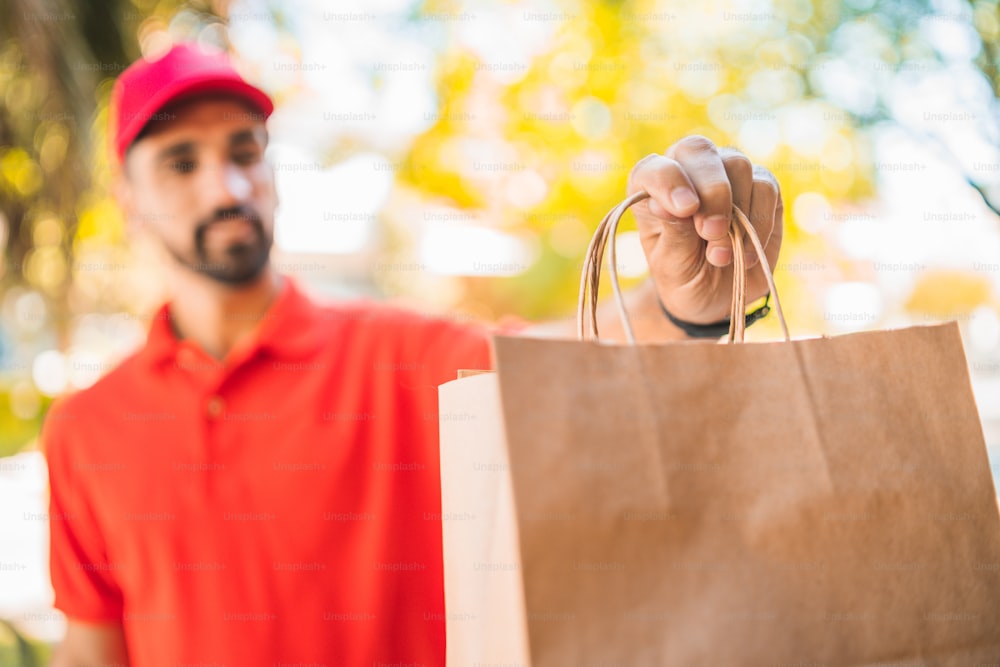 Portrait of a delivery man carrying packages while making home delivery to his customer. Delivery and shipping concept.