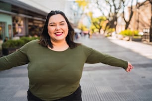 Portrait of young plus size woman smiling while standing outdoors at the street. Urban concept.