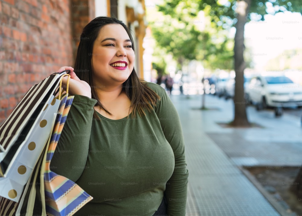 Portrait of young plus size woman holding shopping bags outdoors on the street. Shopping and sale concept.