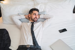 Retrato de un joven empresario que se toma un descanso del trabajo y se relaja después de un duro día en la habitación del hotel. Concepto de viaje de negocios.