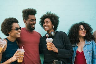 Retrato de amigos afro se divertindo juntos e desfrutando de bons momentos enquanto bebem suco de frutas frescas.