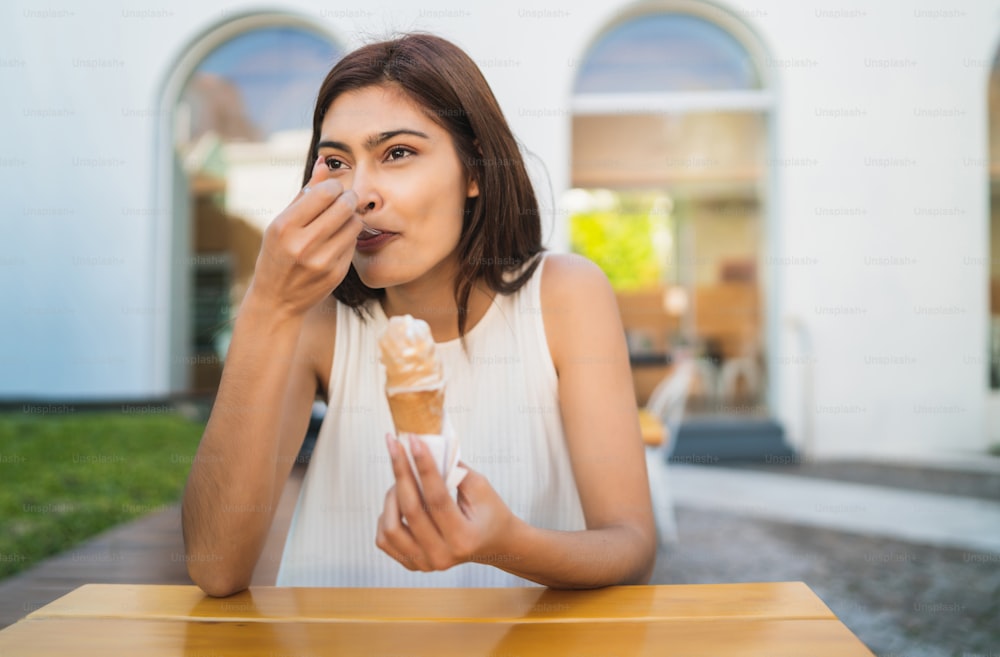 Porträt einer jungen Frau, die sonniges Wetter genießt, während sie im Freien ein Eis isst. Lifestyle-Konzept.