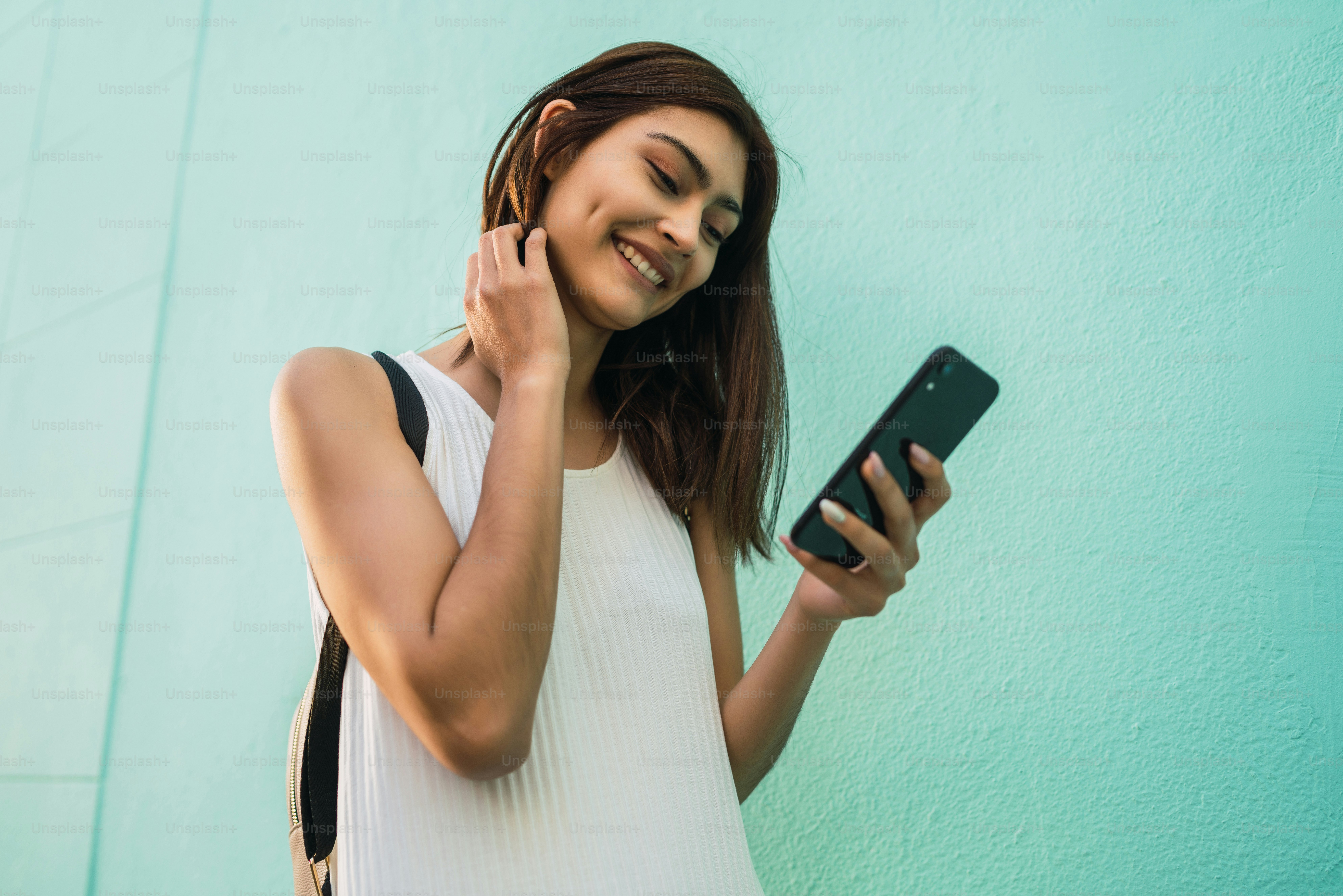 Retrato de uma jovem mulher latina usando seu telefone celular ao ar livre na rua. Conceito urbano e de comunicação.