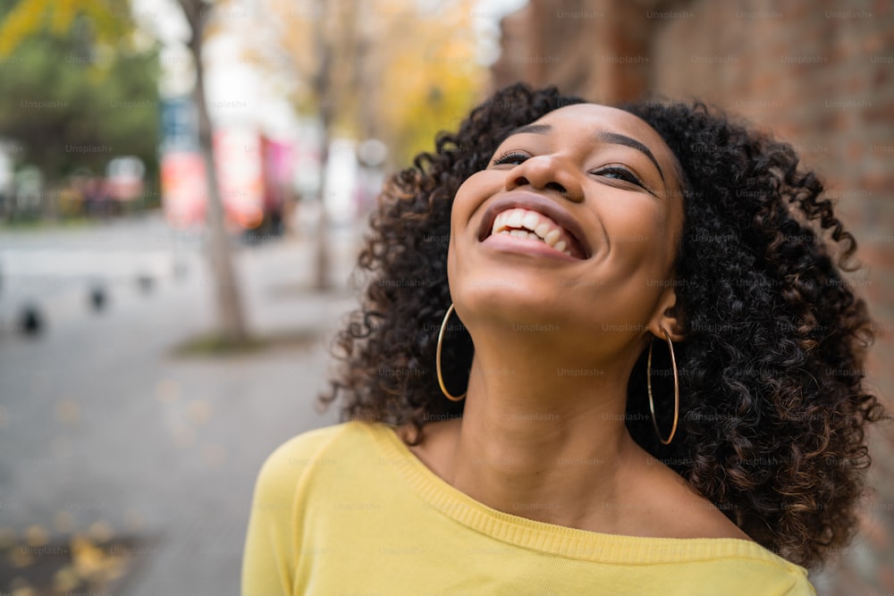 Retrato da bela jovem afro-americana confiante mulher rindo na rua. Ao ar livre.