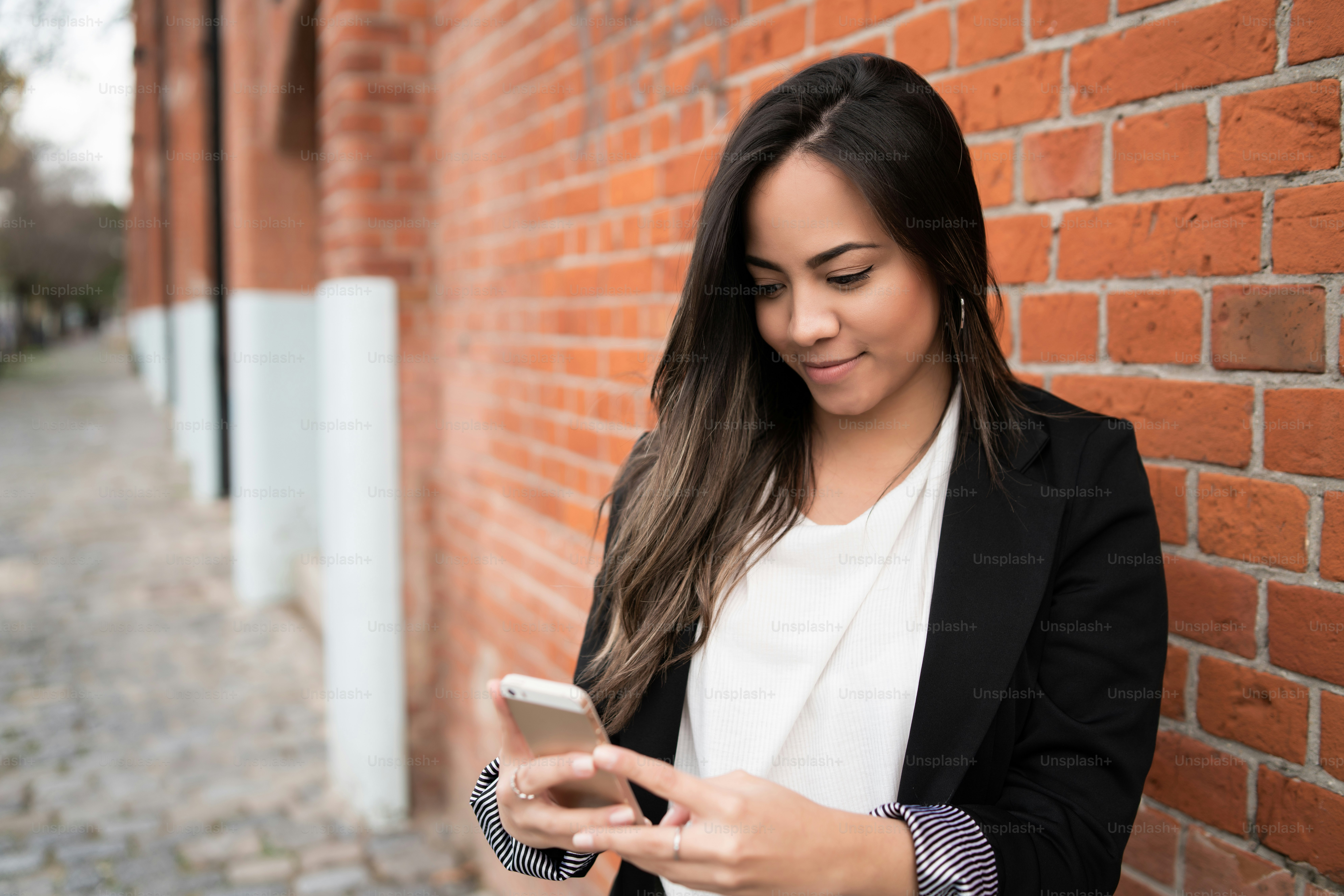 Portrait of young beautiful woman using her mobile phone outdoors in the street. Urban and communication concept.