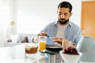 ビーガンの朝食を食べるテーブルに座っている男性