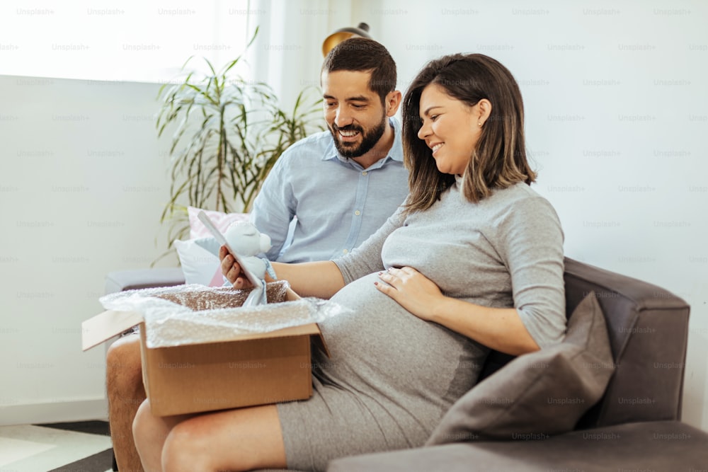 Adult couple expecting baby unpacking baby items purchased online.