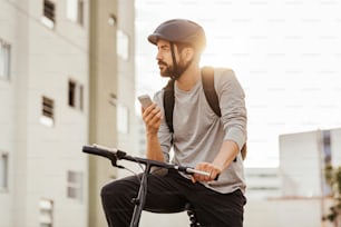 市内でスマートフォンを使って自転車に立つ若者