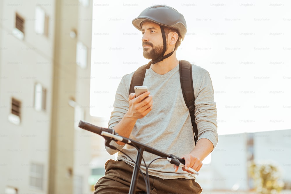 Cycliste debout regardant son smartphone dans la ville. Concept d’utilisation d’applications de carte GPS ou de livraison