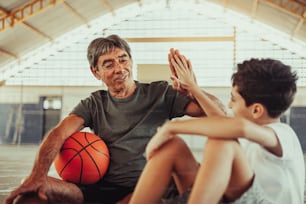 Lateinamerikanischer Großvater und Enkel spielen Basketball auf dem Platz