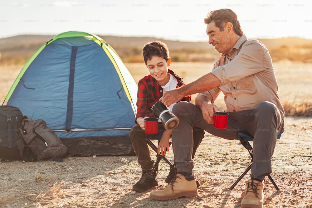 Nonno e nipote che si divertono in campeggio. Concetto di anziani con vita attiva.