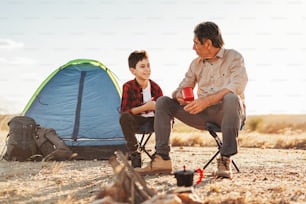 Grandfather and grandson having fun in camping. Concept of elderly people with active life.