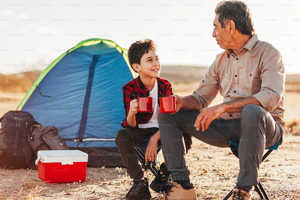 Grandfather and grandson having fun in camping. Concept of elderly people with active life.