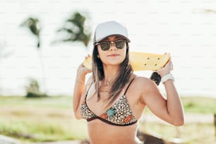 Beautiful young woman with skateboard on the beach