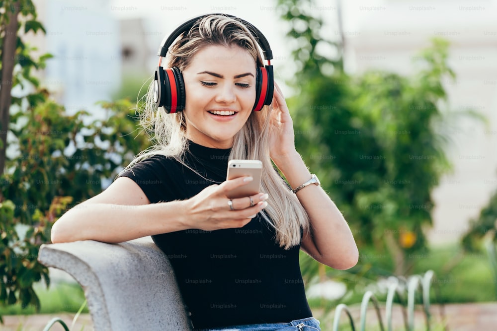 Woman listening to the music from a smart phone with headphones in a park