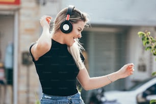 Mulher hipster loira jovem bonita que ouve a música no parque no banco