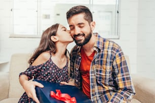 Feliz Dia do Pai! Filha parabenizando o pai e dando-lhe um presente. Papai e filha sorrindo e se abraçando. Férias em família e união