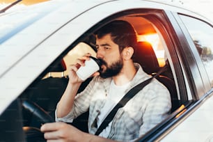 Man drinking coffee while driving his car