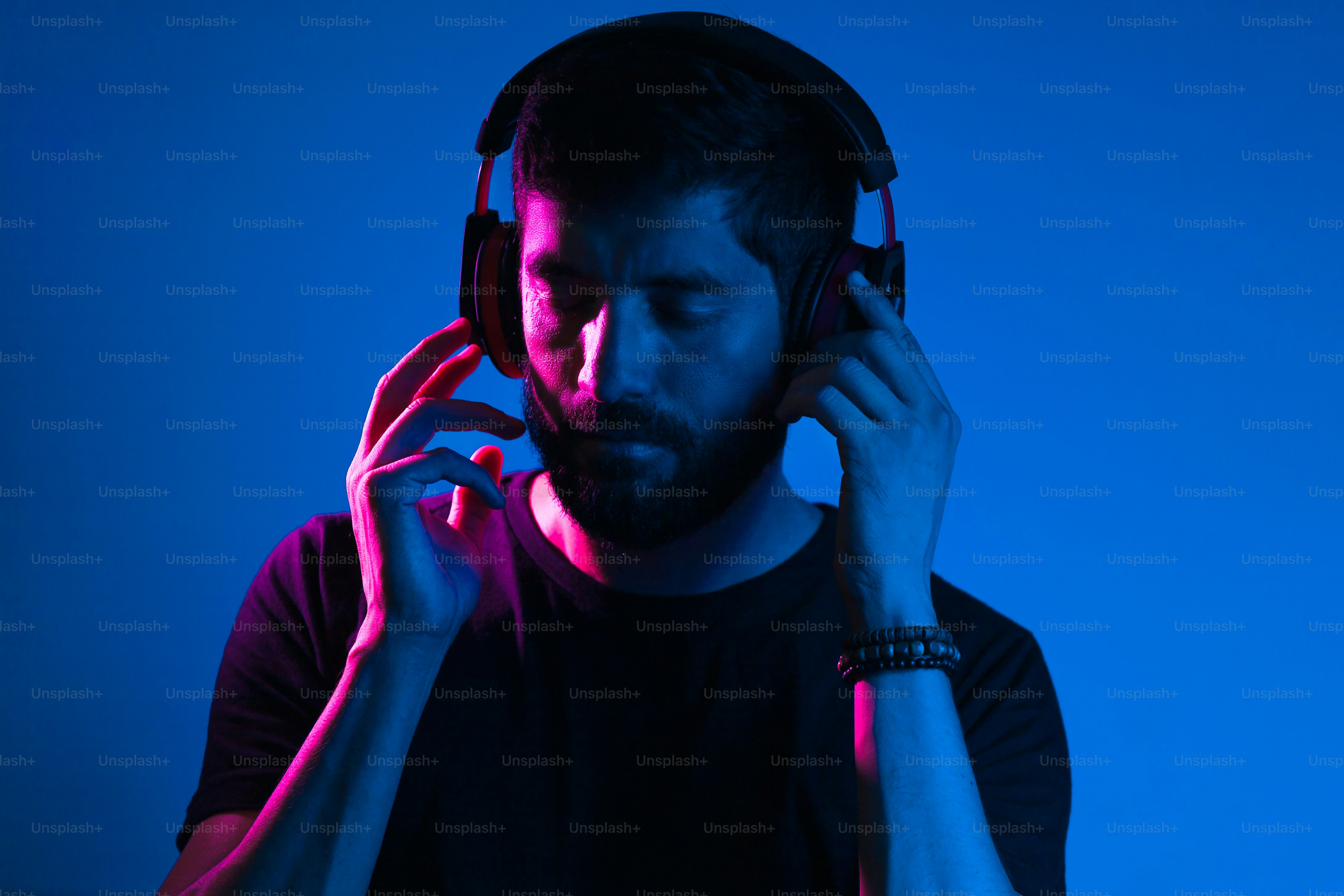 Neon light portrait of bearded man in headphones. Listening to music ...