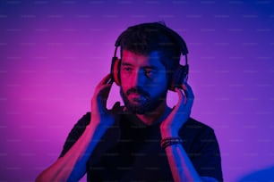 Neon light portrait of bearded man in headphones. Listening to music