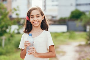 Portrait of cute little girl holding water bottle in the park