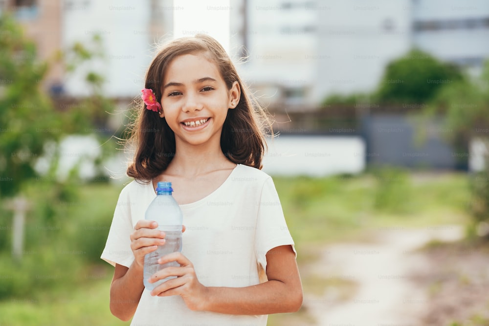 Portrait of cute little girl holding water bottle in the park