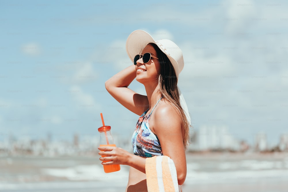 Donna di moda che beve cocktail sulla spiaggia