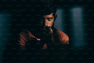 Hombre prisionero en celda oscura deprimido o rezando