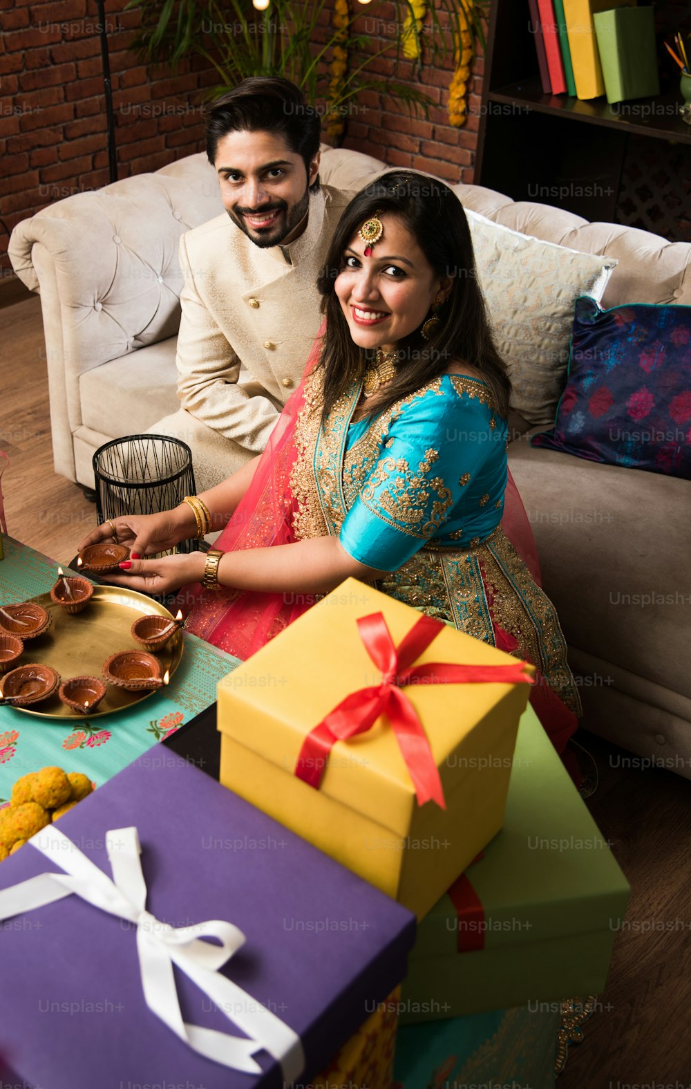 Indian smart couple eating sweet laddu on Diwali or anniversary, selective focus