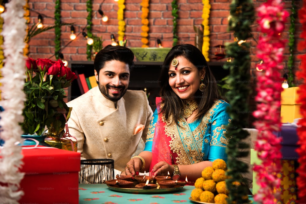 Indian smart couple eating sweet laddu on Diwali or anniversary, selective focus