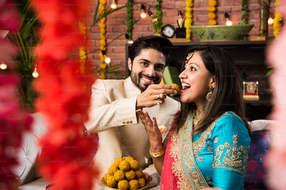Indisches kluges Paar, das süßes Laddu an Diwali oder Jubiläum isst, selektiver Fokus