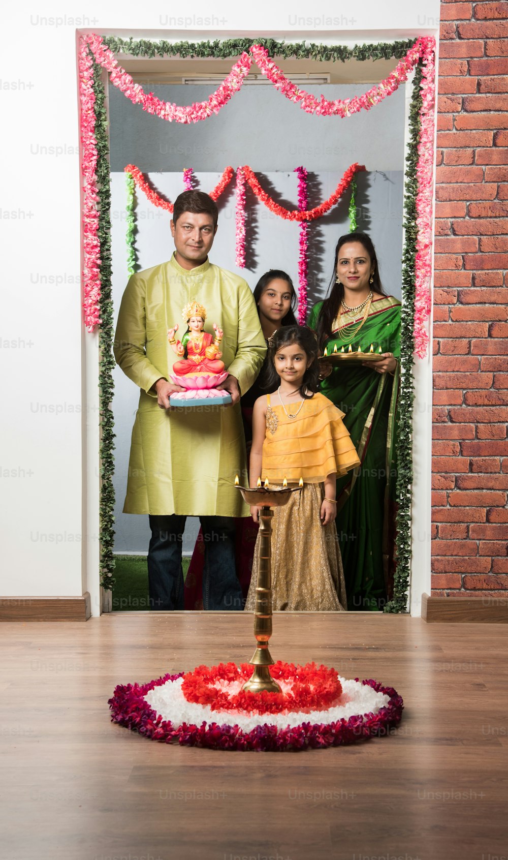 Griha pravesh o Gruha Pravesh - Familia india de cuatro personas que sostiene y trae a casa a la madre Laxmi o ídolo de Lakshmi con puja thali