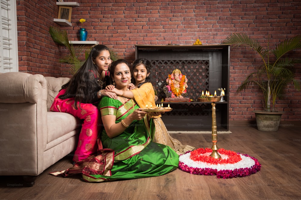 Mãe e filha que fazem rangoli de flor e menina iluminação diya ou samai
